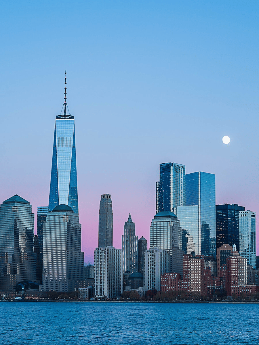 City skyline at dusk with pink sky and moon